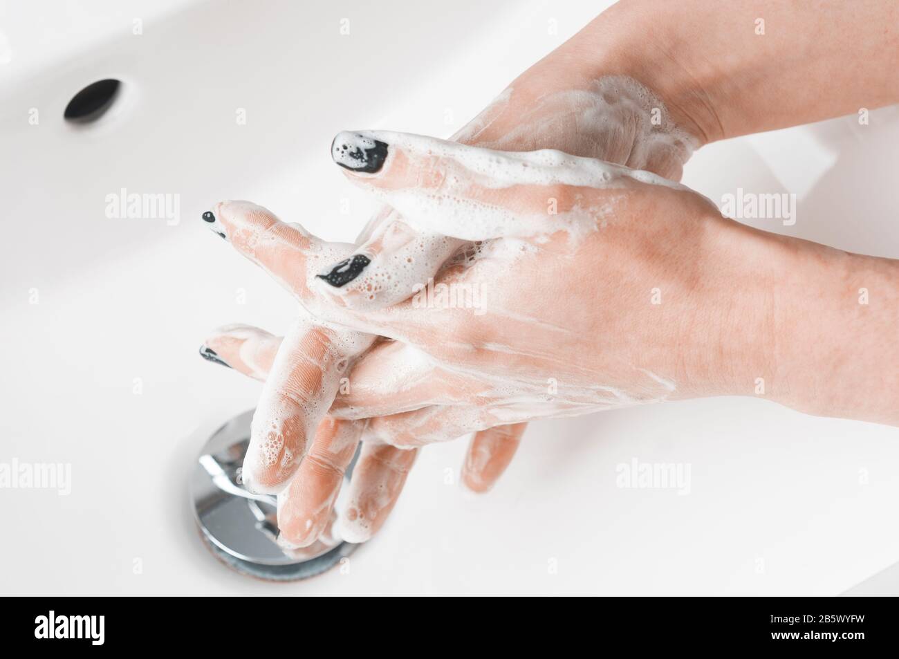 Effective handwashing techniques: woman washing hand with the between the fingers technique. Hand washing is very important to avoid the risk of conta Stock Photo