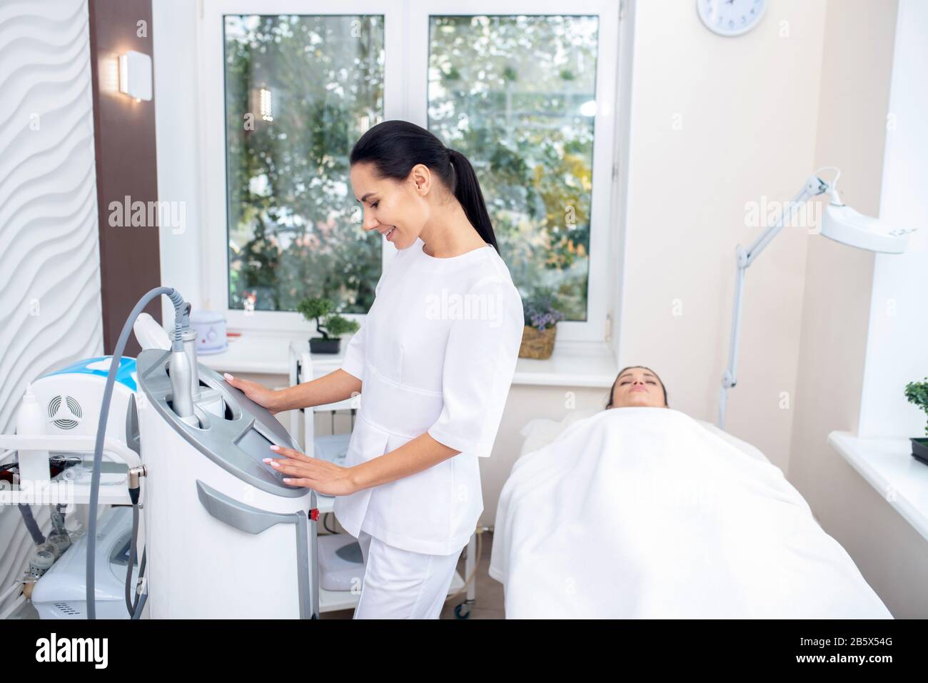 Massage specialist wearing white uniform using modern equipment Stock