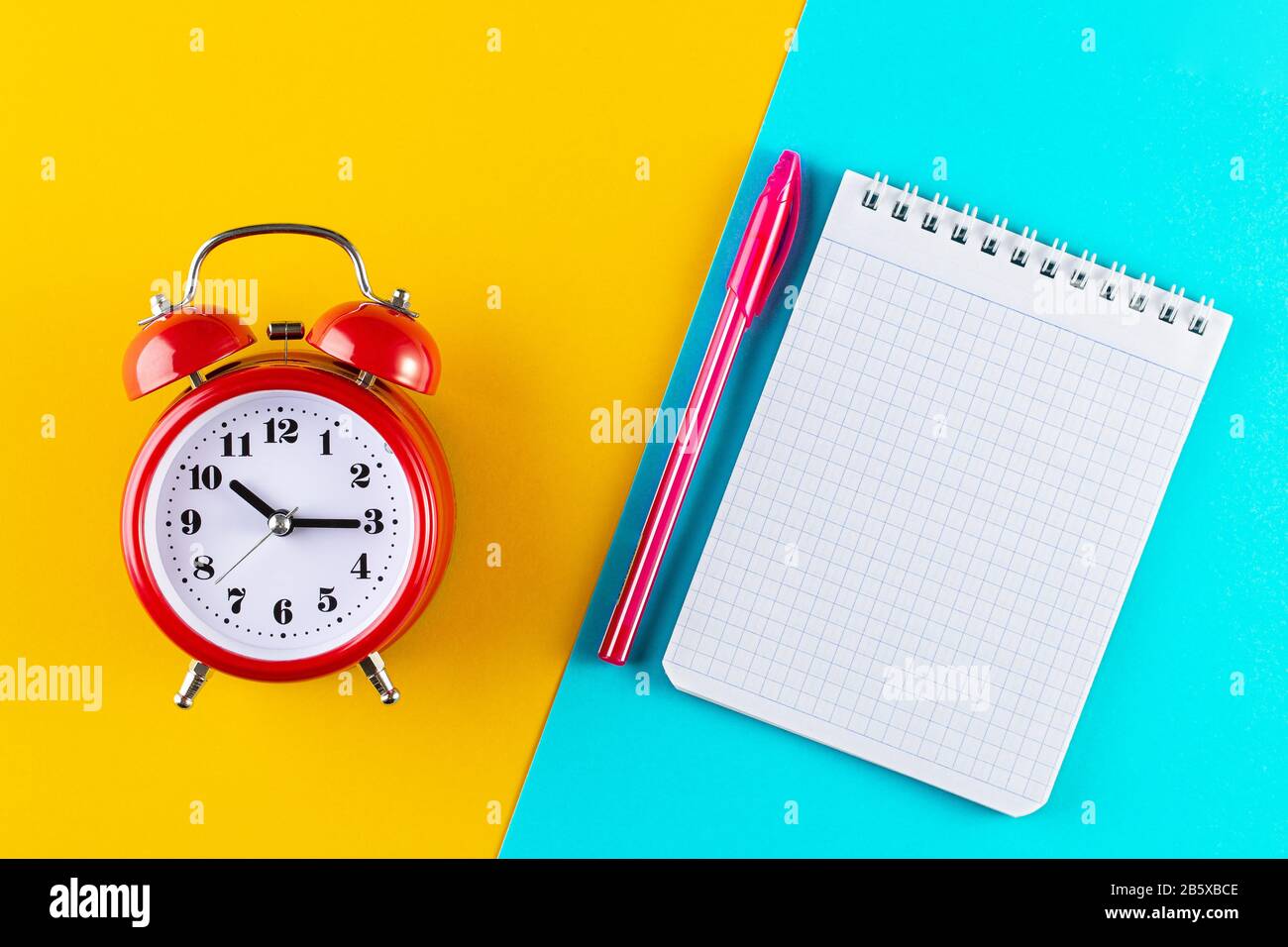Retro alarm clock next to a pen and notebook on a blue and yellow ...