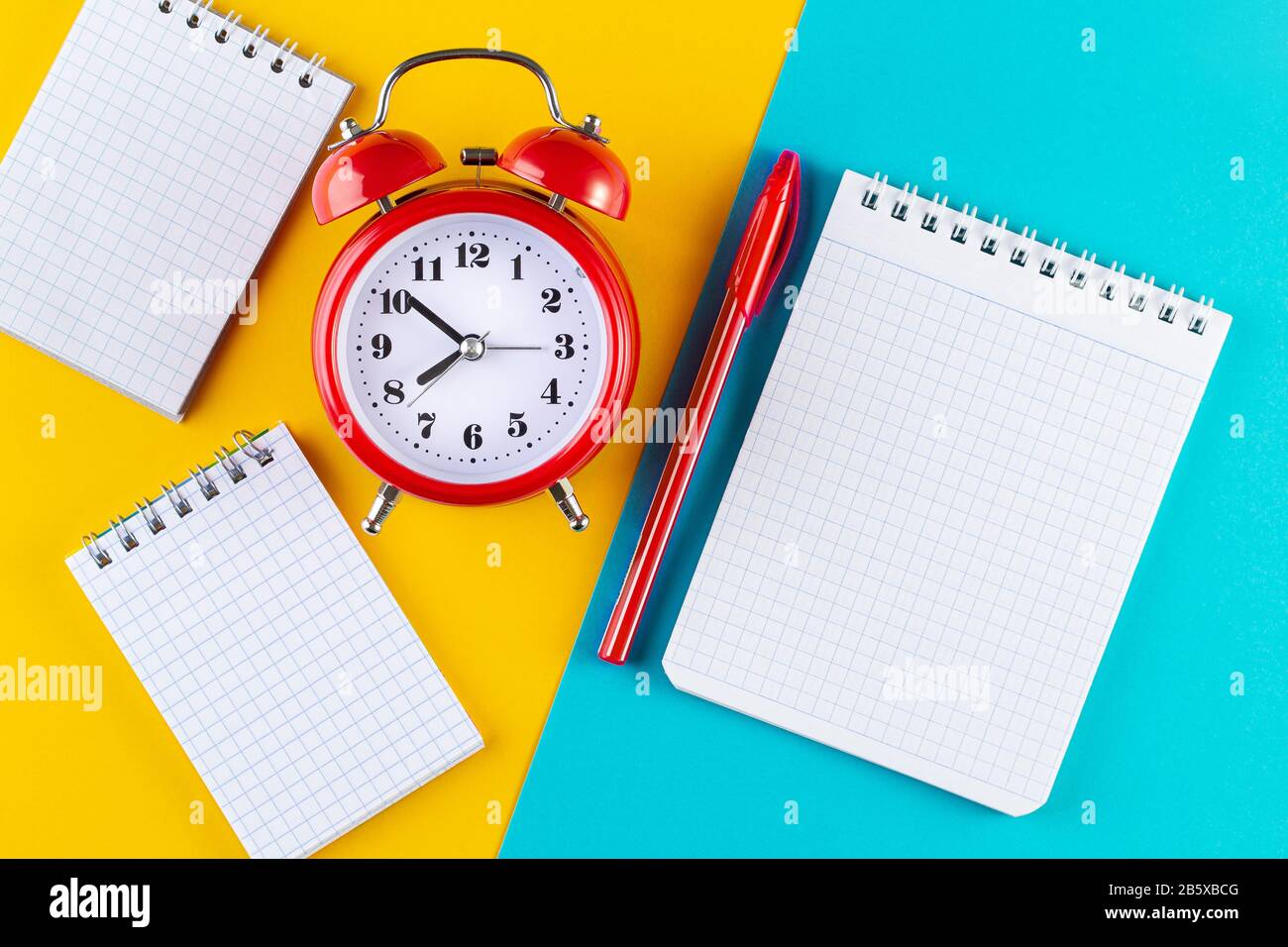 Retro alarm clock next to a pen and notebook on a blue and yellow ...
