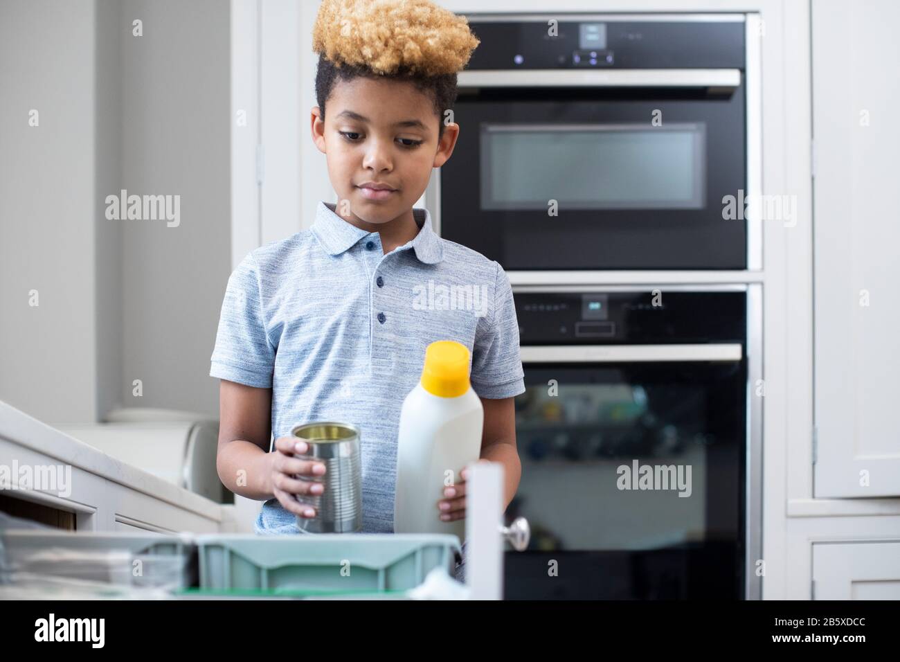 Boy Sorting Recycling Into Kitchen Bin At Home Stock Photo