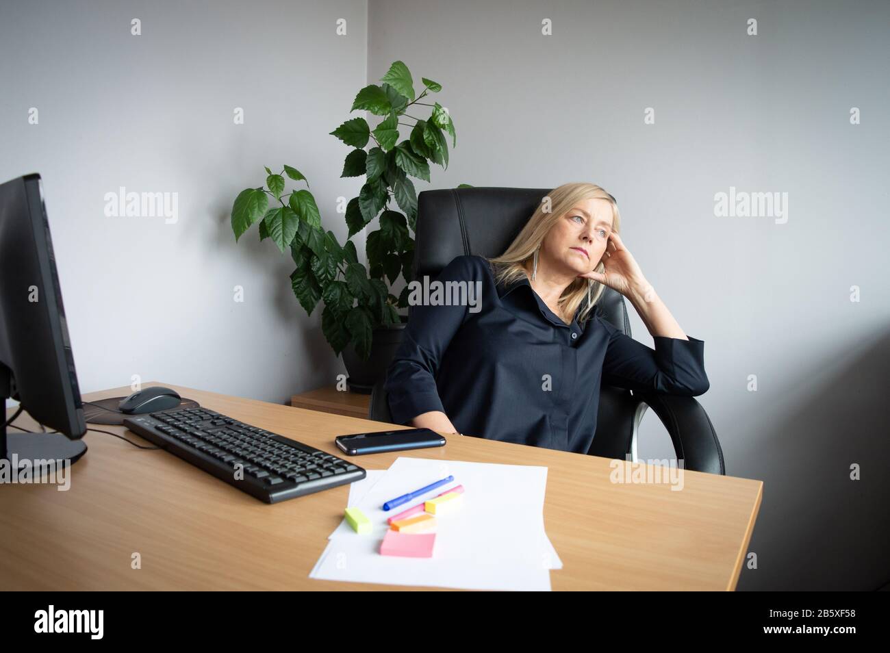 Bored person. Business stagnation. Working from home. Distant working. Woman in office at her desk having a break from computer work Stock Photo