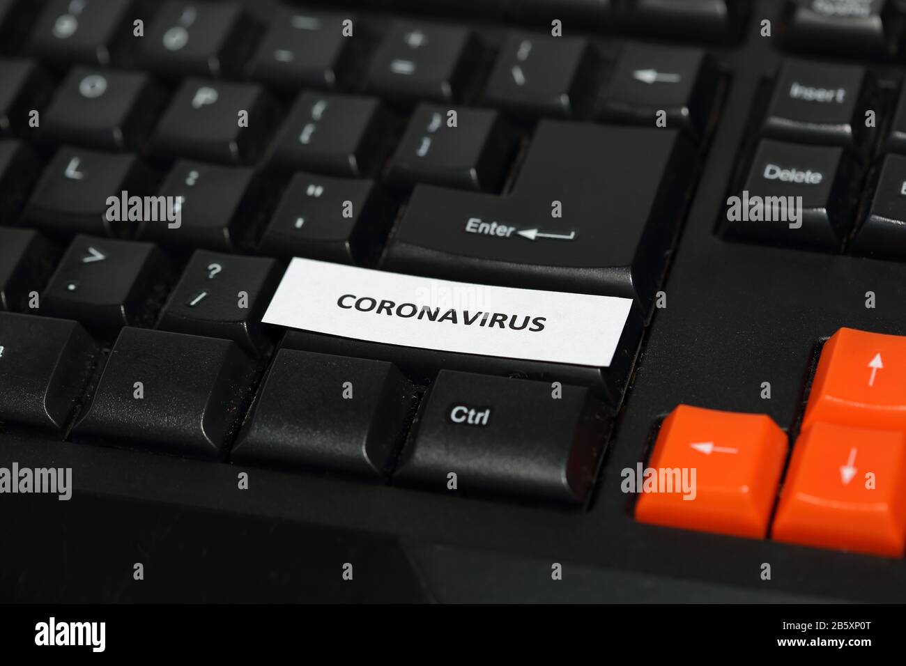 Black computer keyboard with few orange buttons, on one button inscription text CORONAVIRUS. Stock Photo