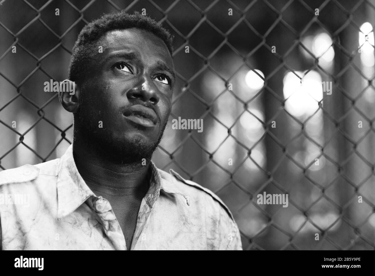 Face of young homeless African man looking up in black and white Stock Photo