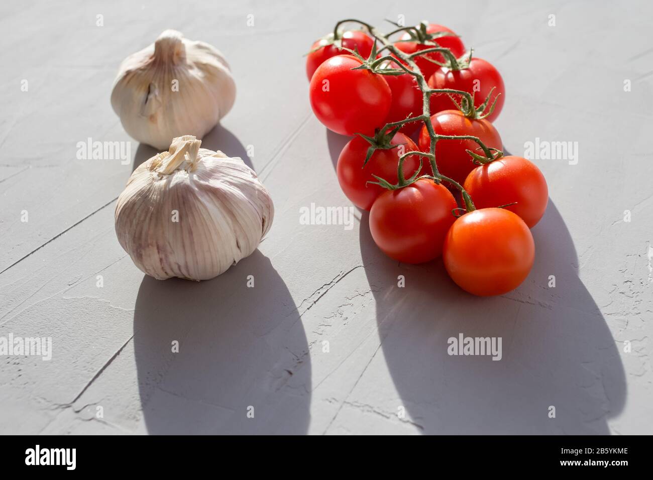 Fresh tomatoes and garlic on a grey background. Ingredients for ketchup. Stock Photo
