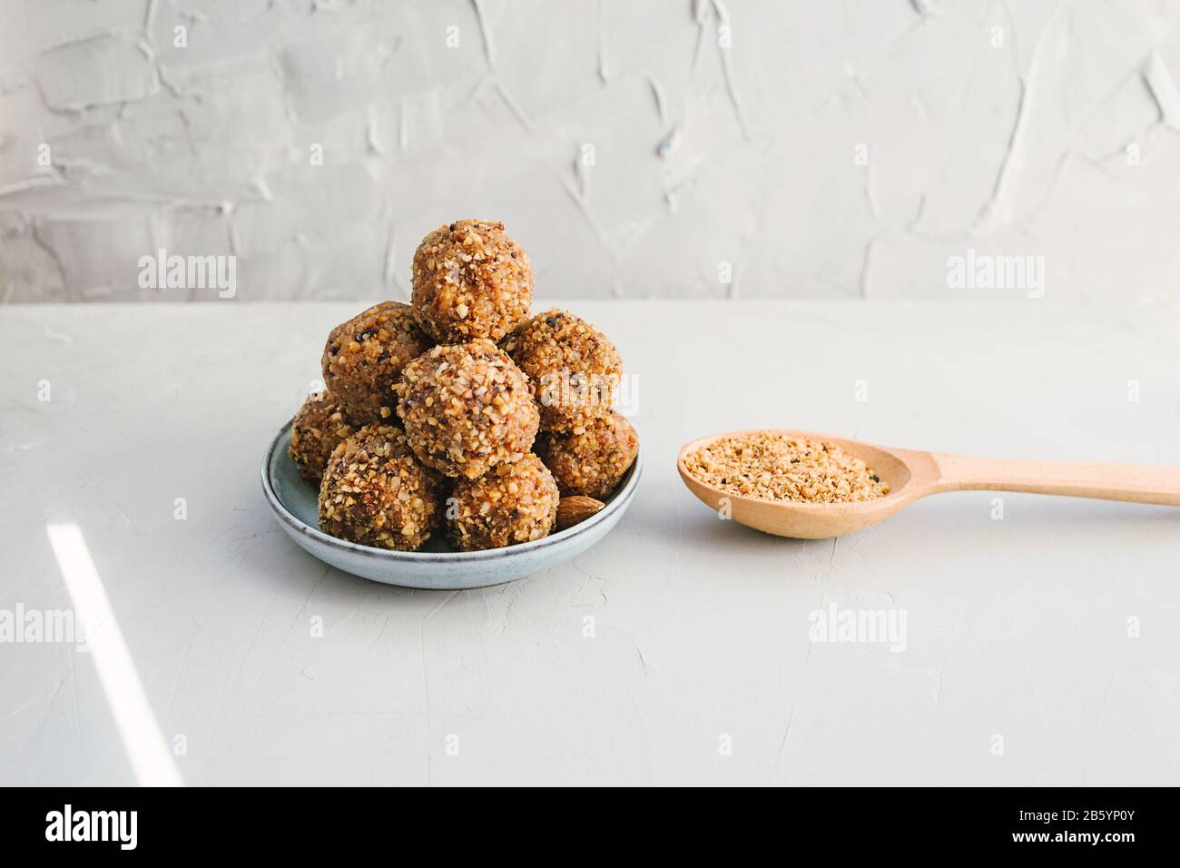 Homemade energy balls with dried apricots, raisins, dates, walnuts, almonds and coconut. Healthy sweet food with nut shavings. Vegan vegetarian raw sn Stock Photo