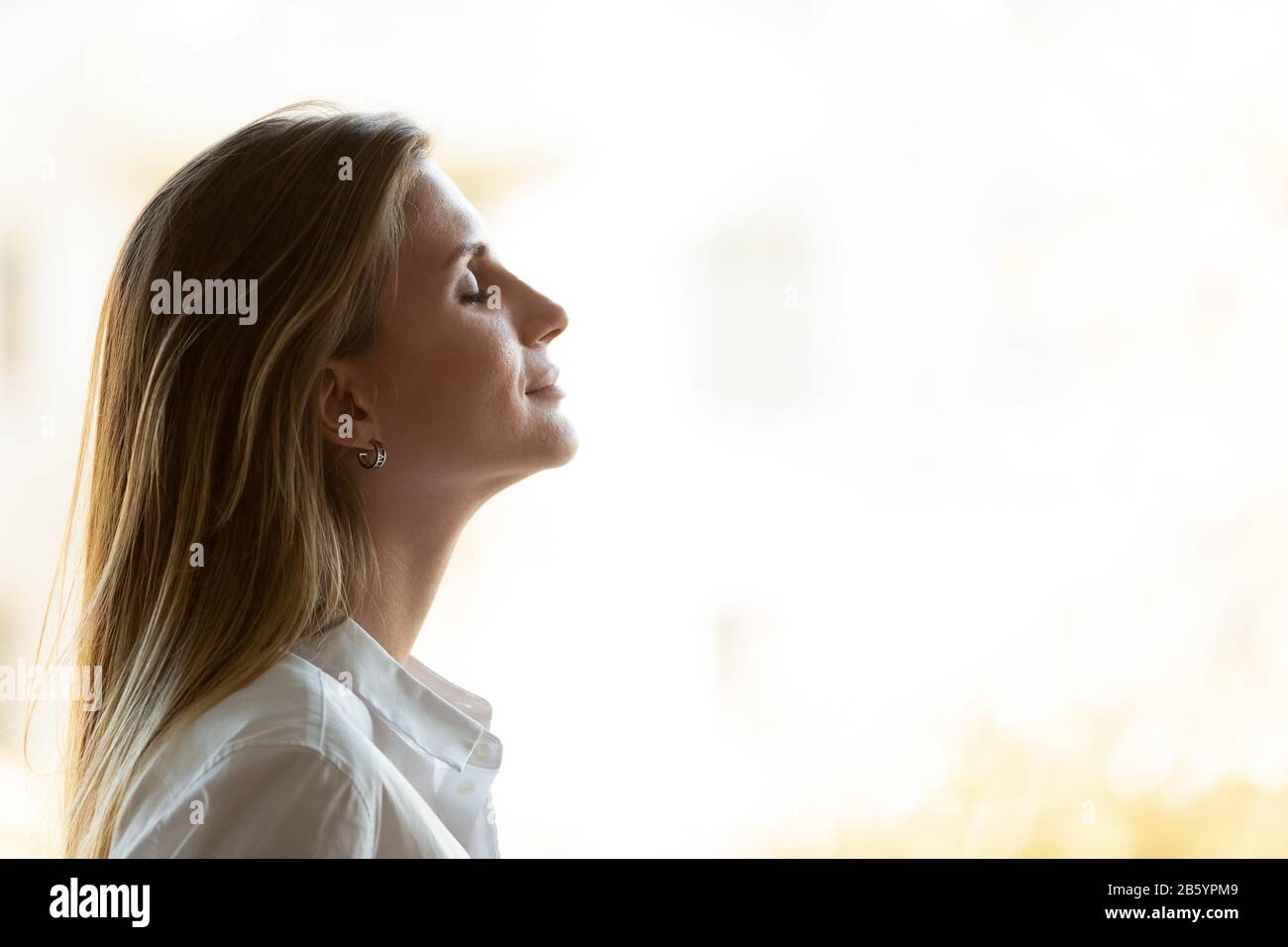 Head shot young mindful businesswoman breathing fresh air. Stock Photo