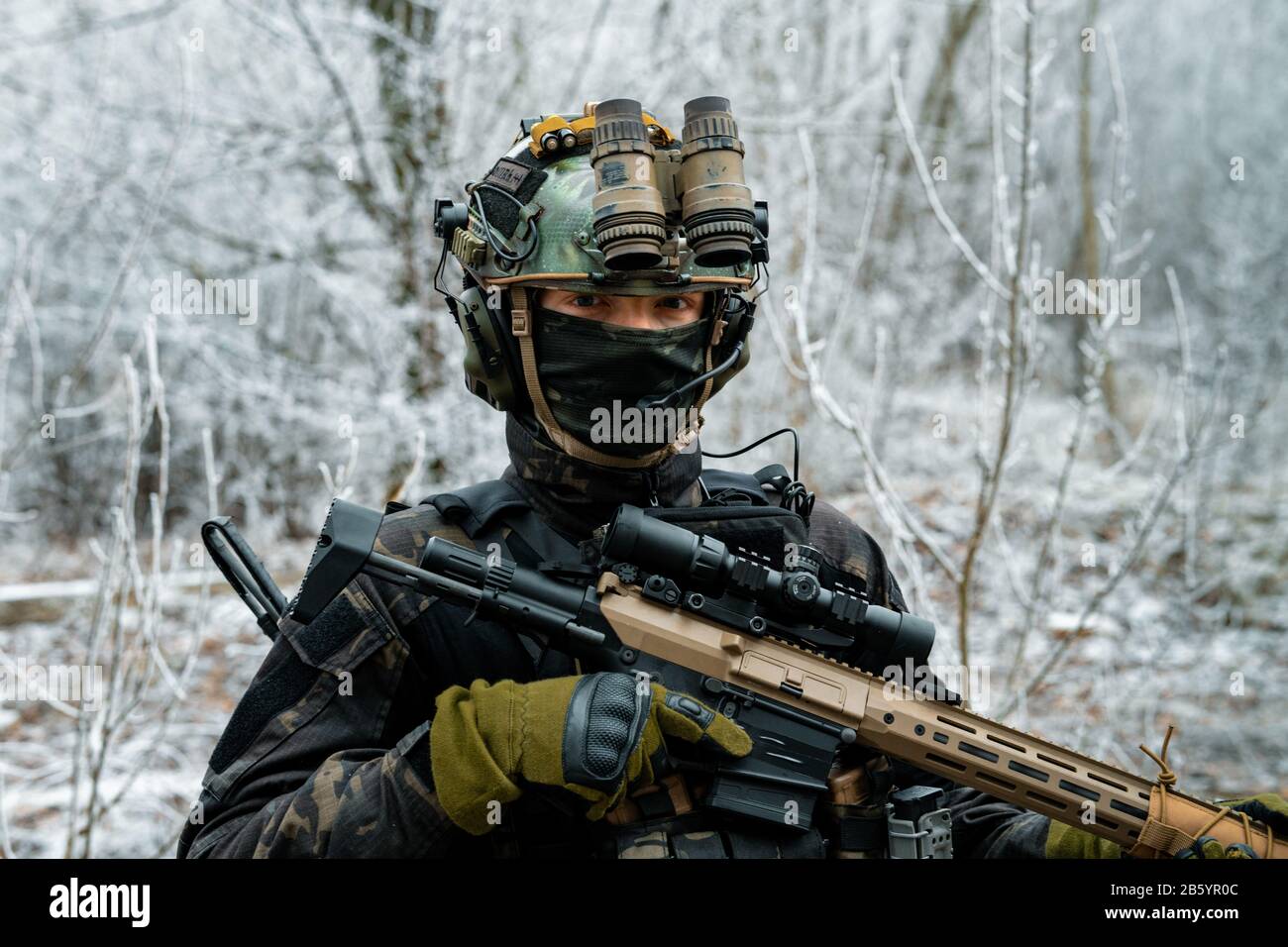 Airsoft man in black camouflage uniform with machinegun with optical