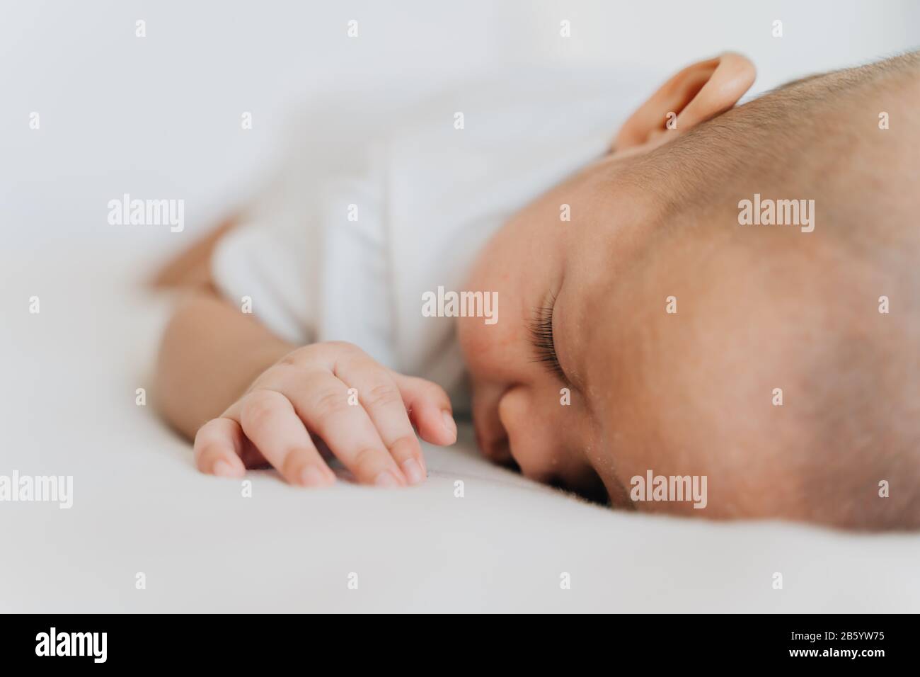 Newborn baby kid sleeping on his stomach on bed at home. Asian child