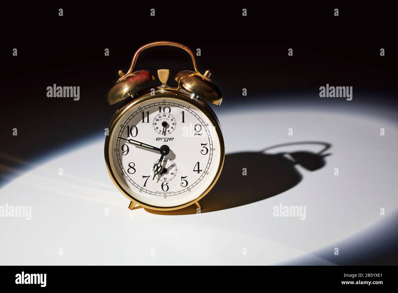Old fashioned mechanical alarm clock with bells on top with hands at twelve minutes to seven Stock Photo