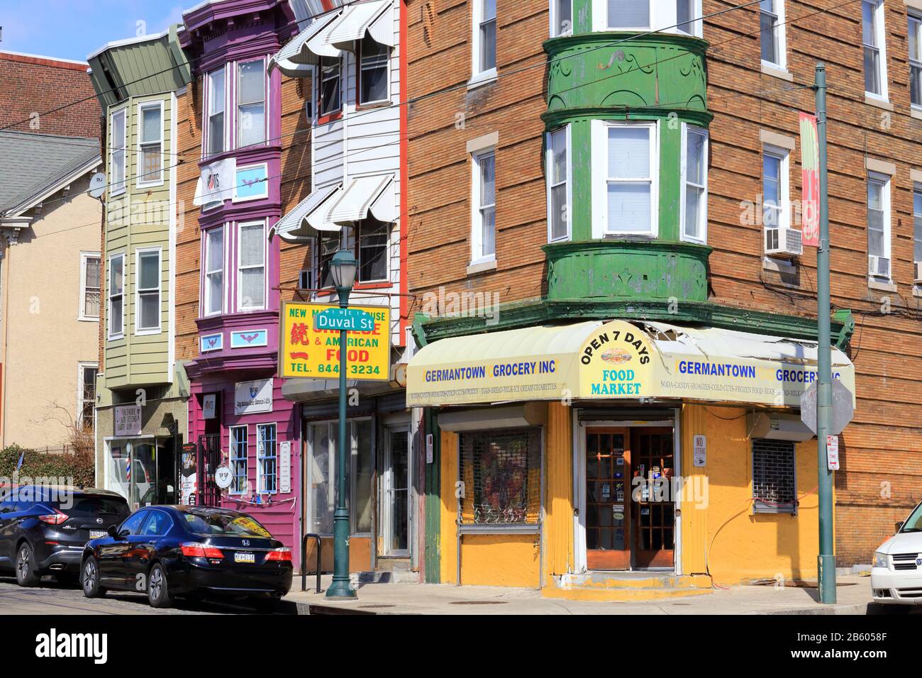 A colorful corner of Germantown with row houses and a corner store at the intersection of Duval St, and Germantown Avenue, Philadelphia, PA. Stock Photo
