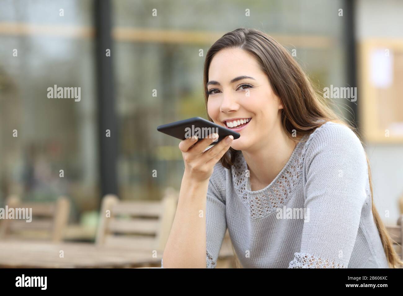 Happy woman using voice recognition system on her smart phone on a coffee shop terrace Stock Photo