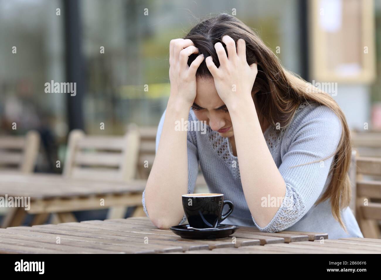 Sad woman complaining alone sitting on a coffee shop terrace Stock Photo