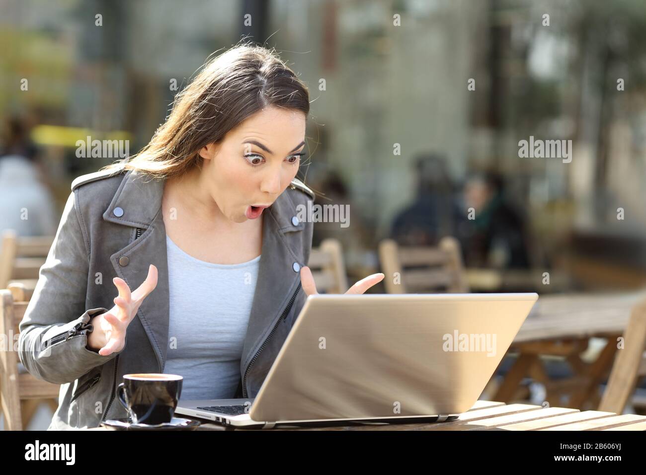 Reading Computer Amazed Amazed woman reading surprising news on her laptop on a cafe terrace ...