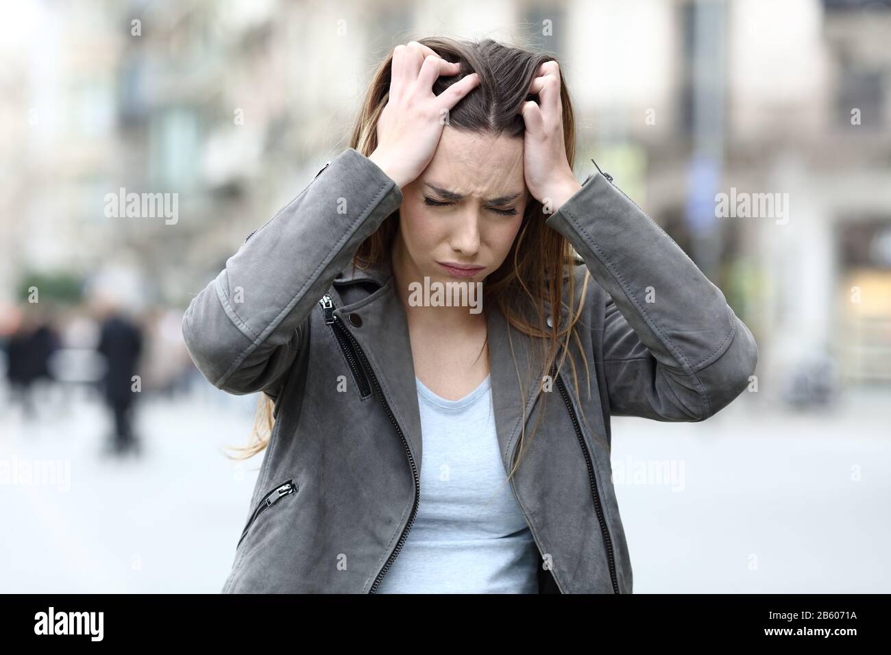 Stressed young girl grabbing her head complaining alone on city street Stock Photo