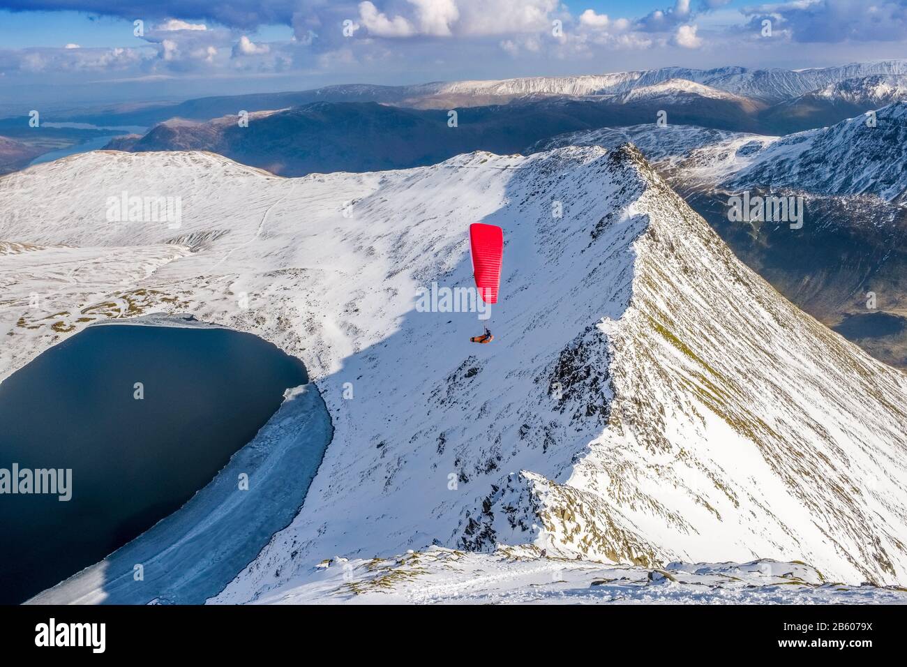 a paraglider flying over Striding Edge on Helvellyn in winter. Lake District National Park, Cumbria,UK Stock Photo