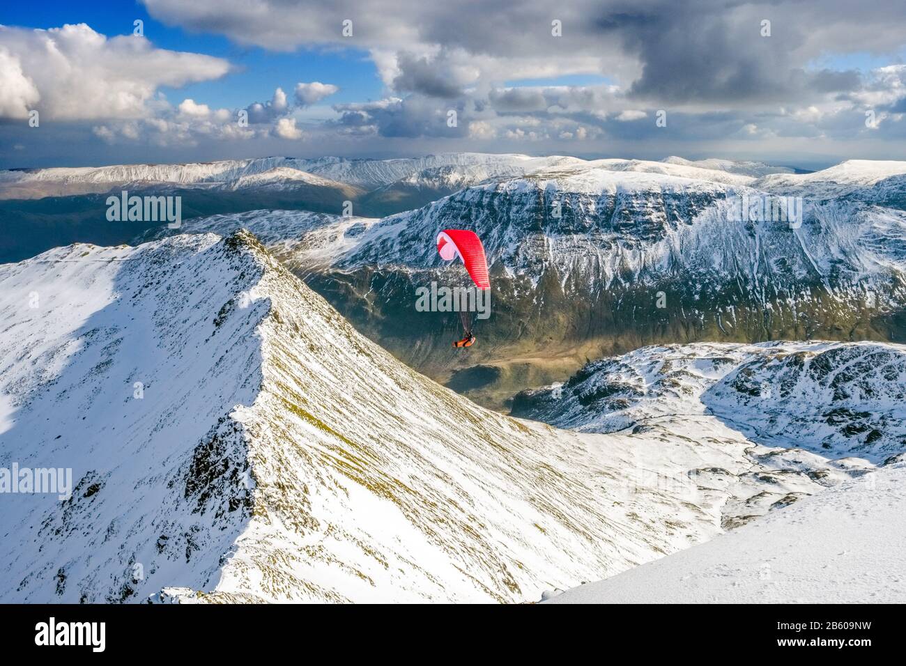 a paraglider flying over Striding Edge on Helvellyn in winter. Lake District National Park, Cumbria,UK Stock Photo