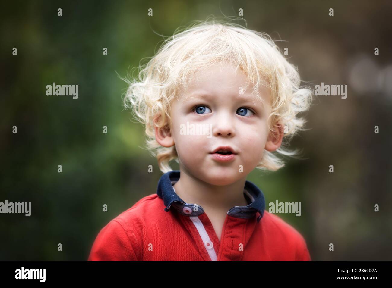 Small boy playing outside. Portrait of 2 year old toddler with blond