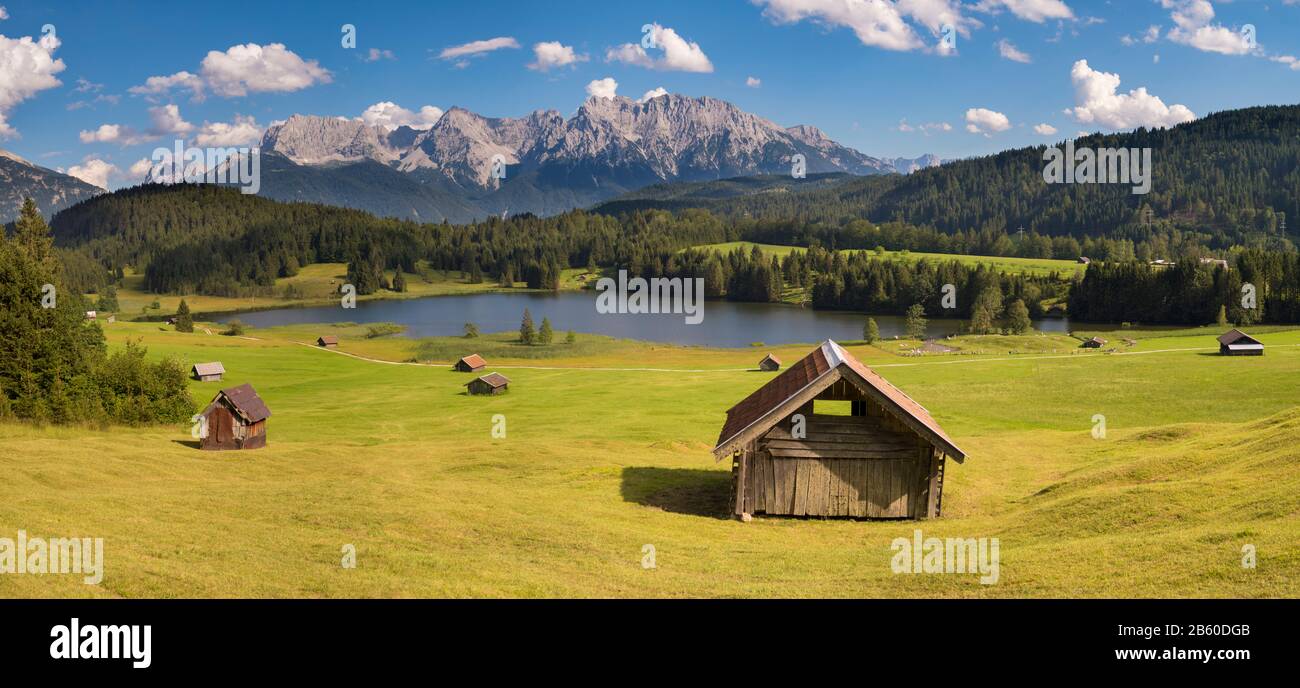 panoramic landscape with meadow and lake in front of alps mountains Stock Photo