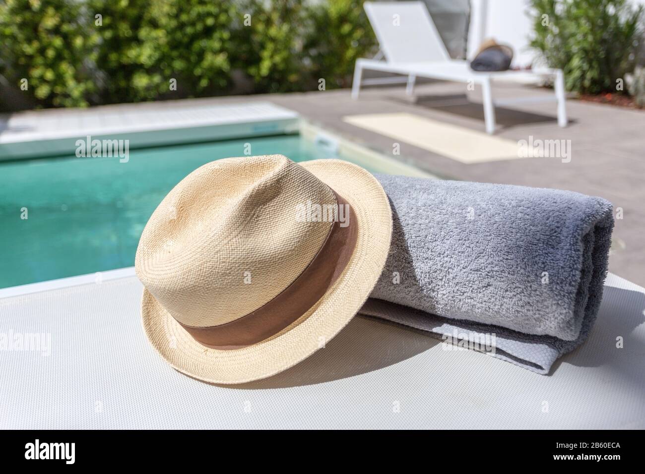 Straw hat on the sun lounger by the pool. Vacation with a tourist