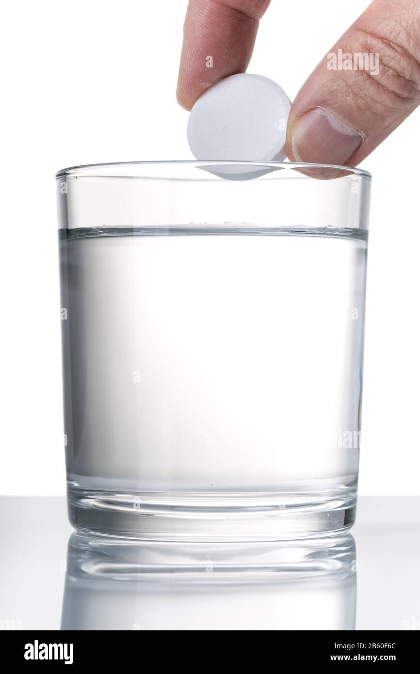 Hand throws aspirin tablet into water. Close up Stock Photo