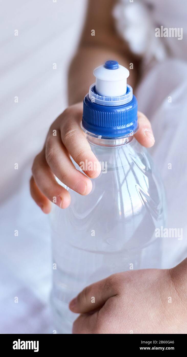 Young little girl hold water bottle. Kid drink cold fresh. Thirsty