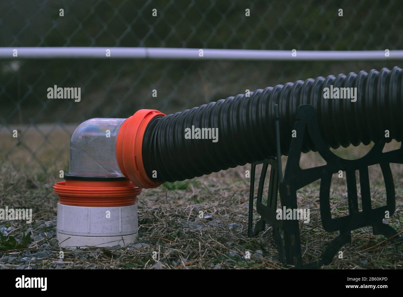 RV sewer hose connected to dump station with 90 degree clear fitting Stock Photo