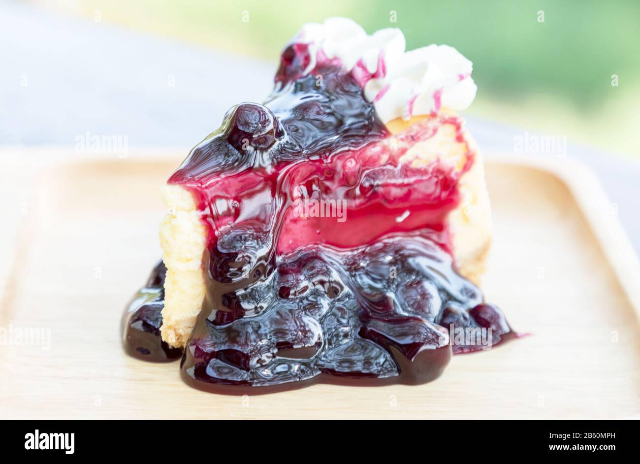 Blueberry cheesecake with cream on wooden plate on wood table at restaurant. Stock Photo