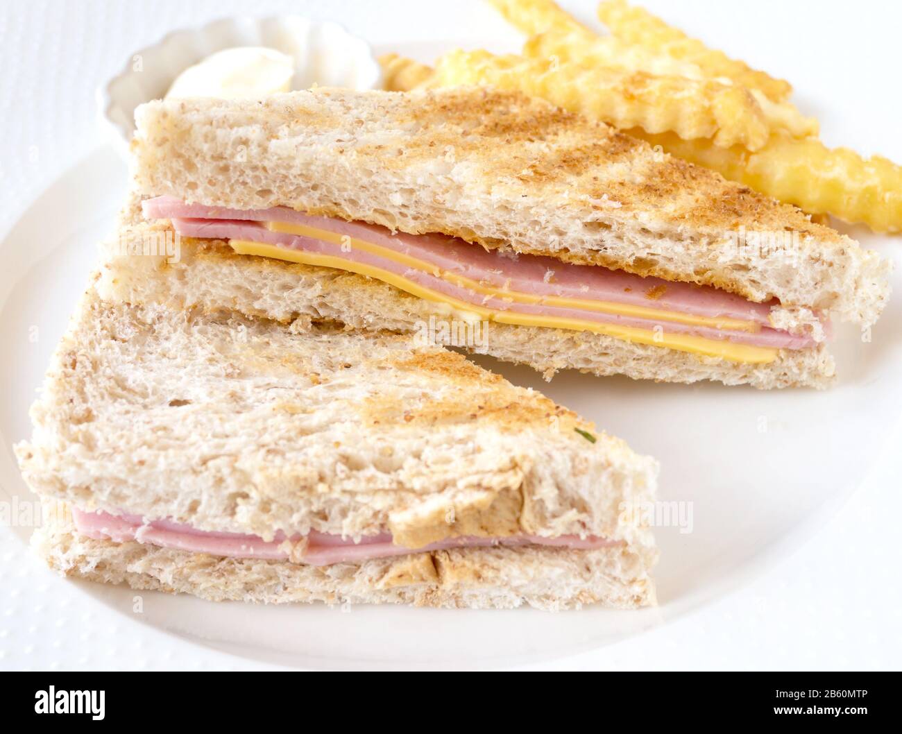Ham and cheese sandwich and French fries with mayonnaise sauce on white