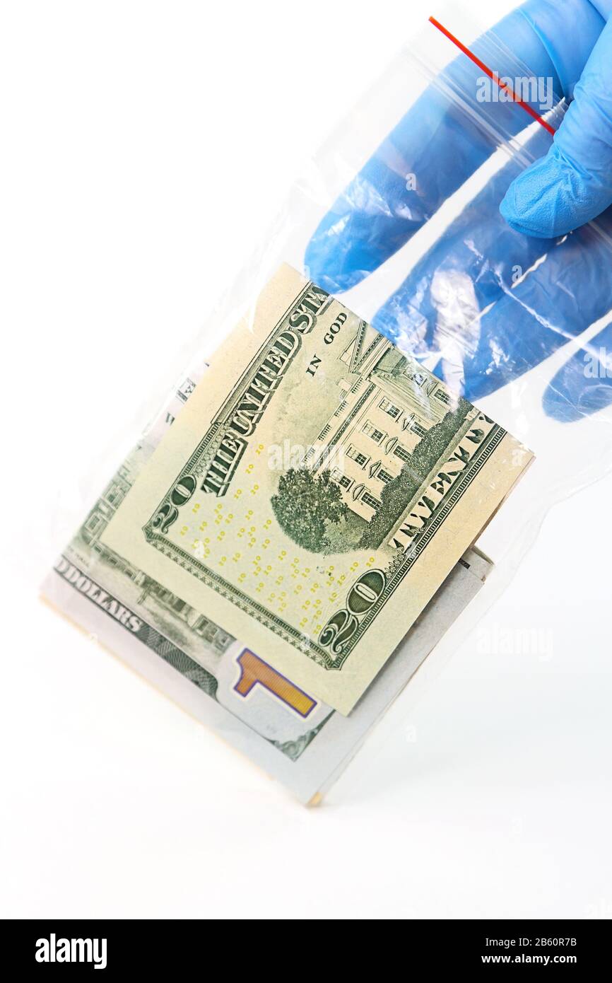 A hand in a medical glove holds a transparent plastic bag with money that is a source of infection Stock Photo