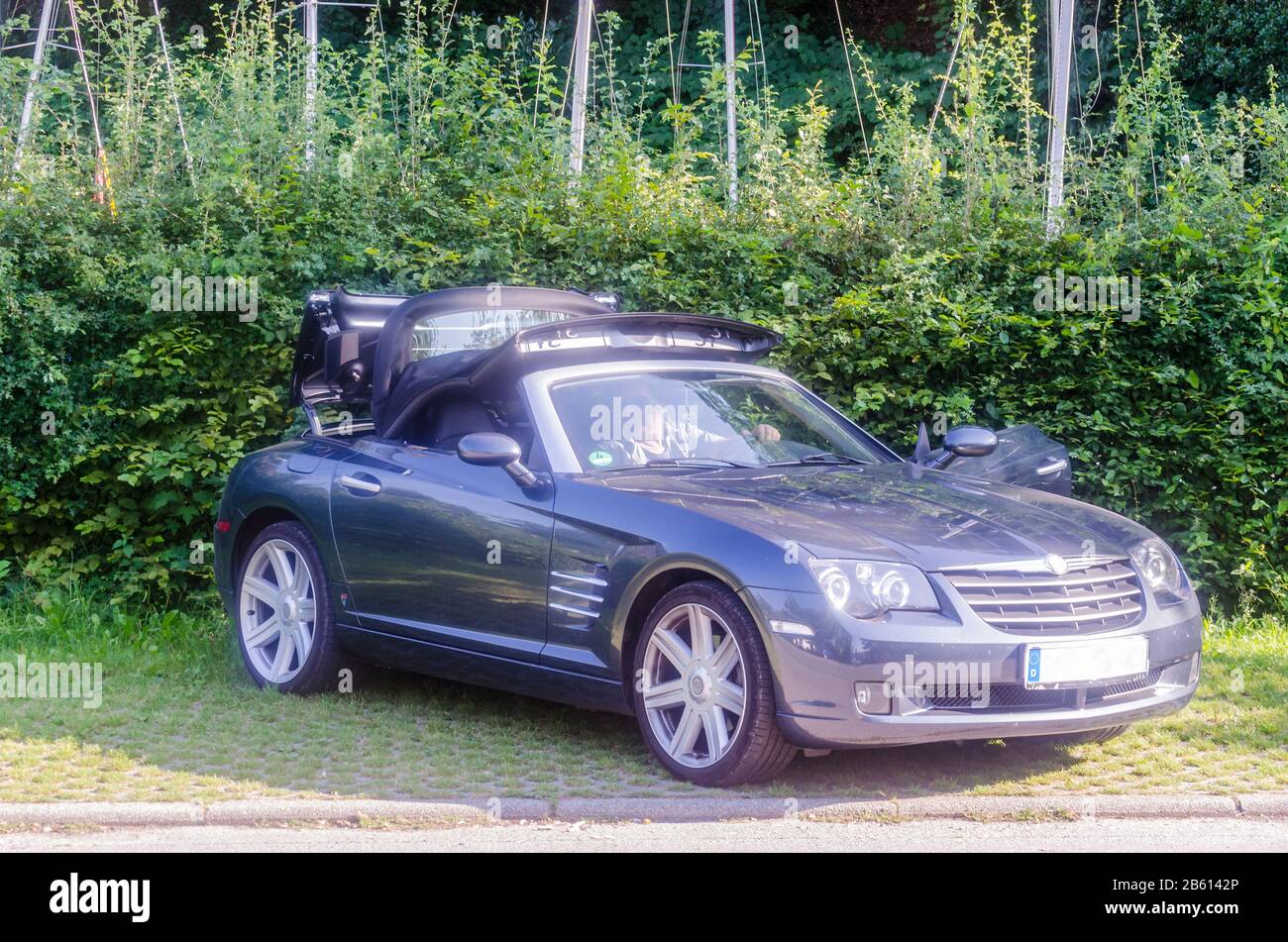 Heiligenhaus, Nrw, Germany - July 31, 2014: A male driver in a Chrysler Crossfire Roadster / Convertible in automatic machine gray, open the soft top Stock Photo