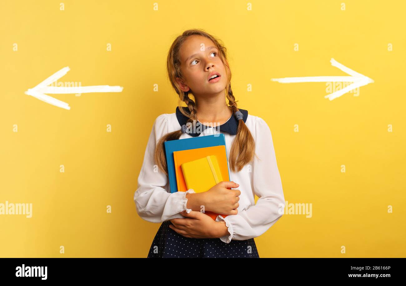 Young student is confused about the right arrow to select. Yellow background Stock Photo