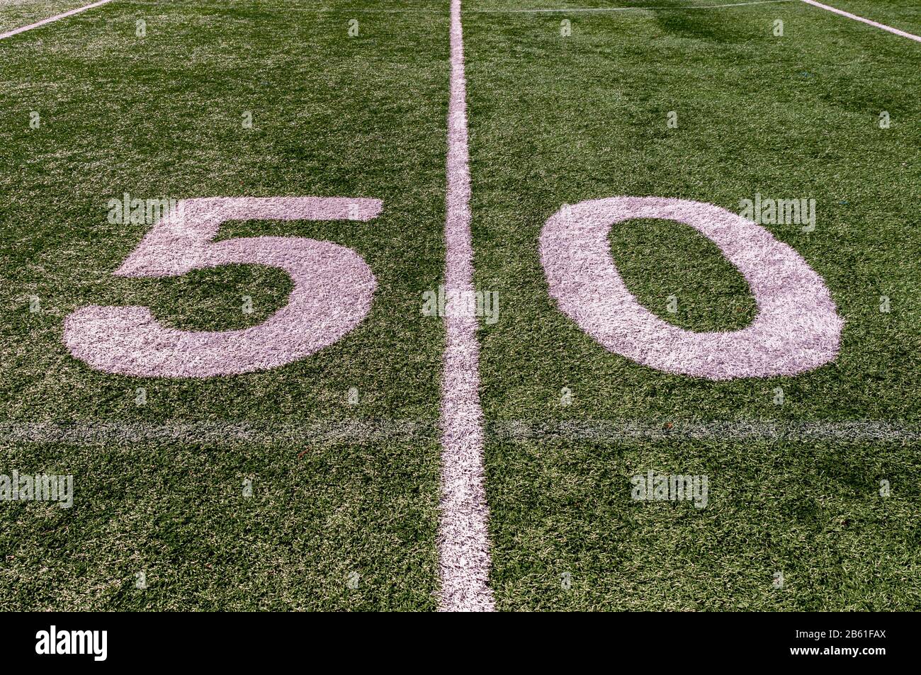 The fifty yard line marker on a football field with green artificial grass and white lines Stock Photo