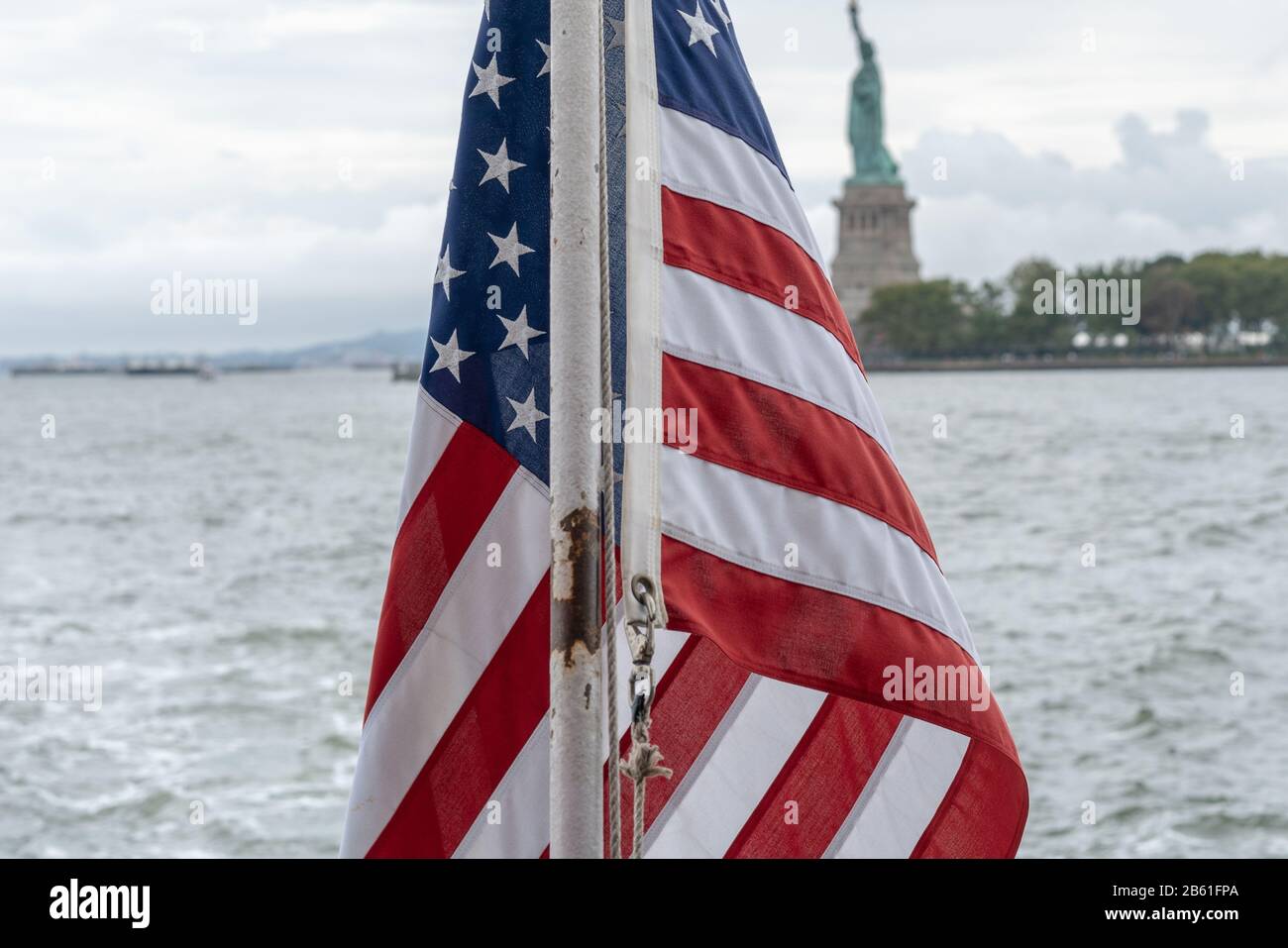 On a New York City ferry with the Statue of Liberty in background and an American flag in the foreground. Stock Photo