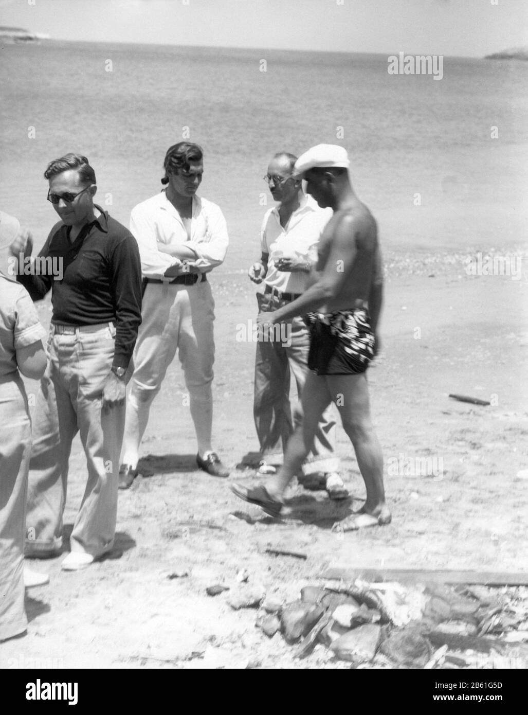 CLARK GABLE candid in costume as Fletcher Christian with film crew on beach on Santa Catalina