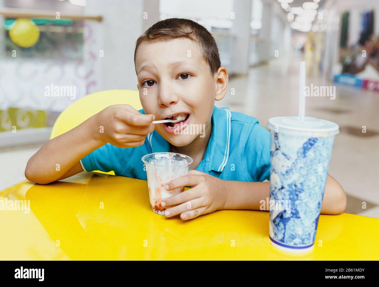 Child boy eating icecream and drinking soda in shopping mall cafe