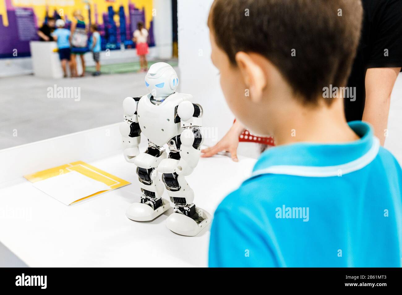 Kid boy playing with interactive robot toy at the exhibition Stock Photo