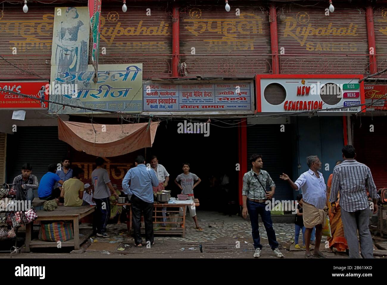 People gathers and chats in front of a street food vendor in Varanasi shopping area. Varanasi City, Uttar Pradesh, India. Stock Photo