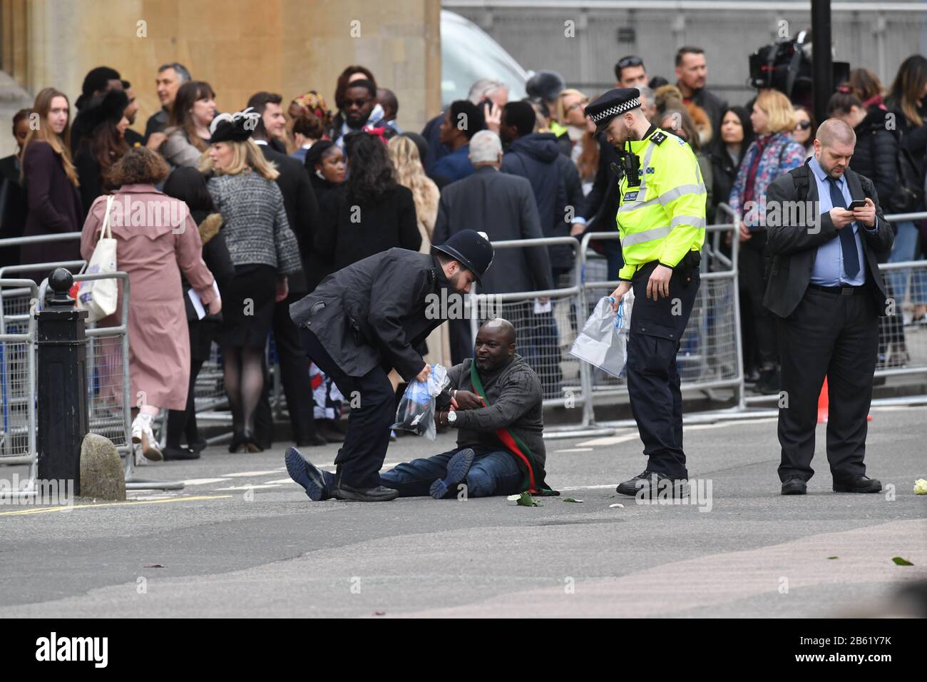 Police officers detain one of two men who ran into the road outside Westminster Abbey, London, ahead of the Commonwealth Service. Stock Photo