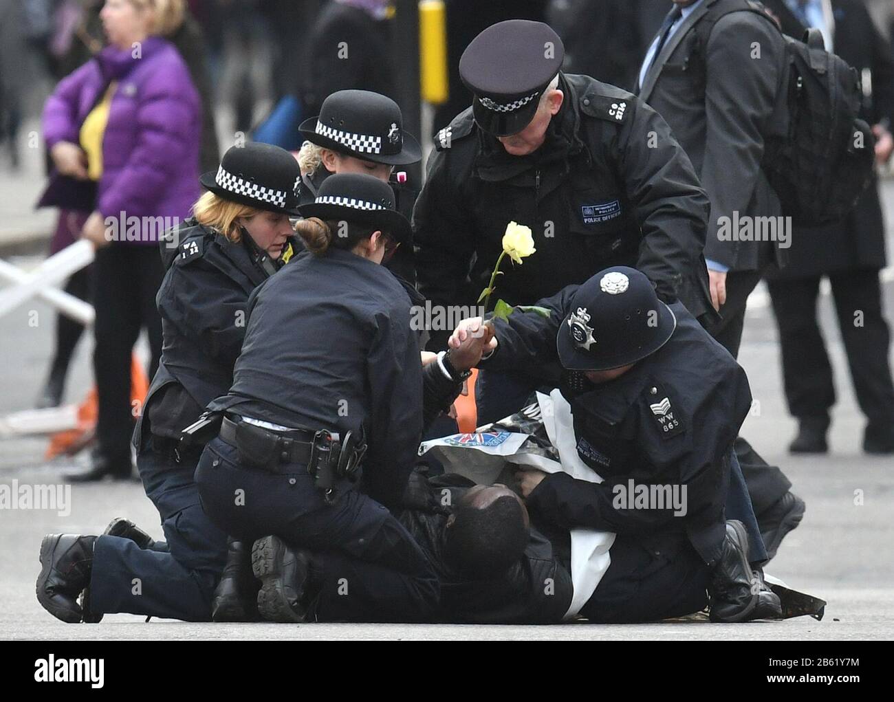 Police officers detain one of two men who ran into the road outside Westminster Abbey, London, ahead of the Commonwealth Service. Stock Photo