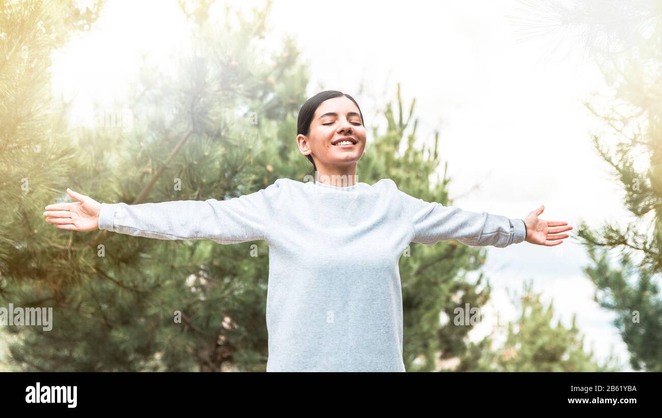 soul and body freedom. attractive woman with arms open and eyes closed meditating and understanding her being in nature at sunrise Stock Photo
