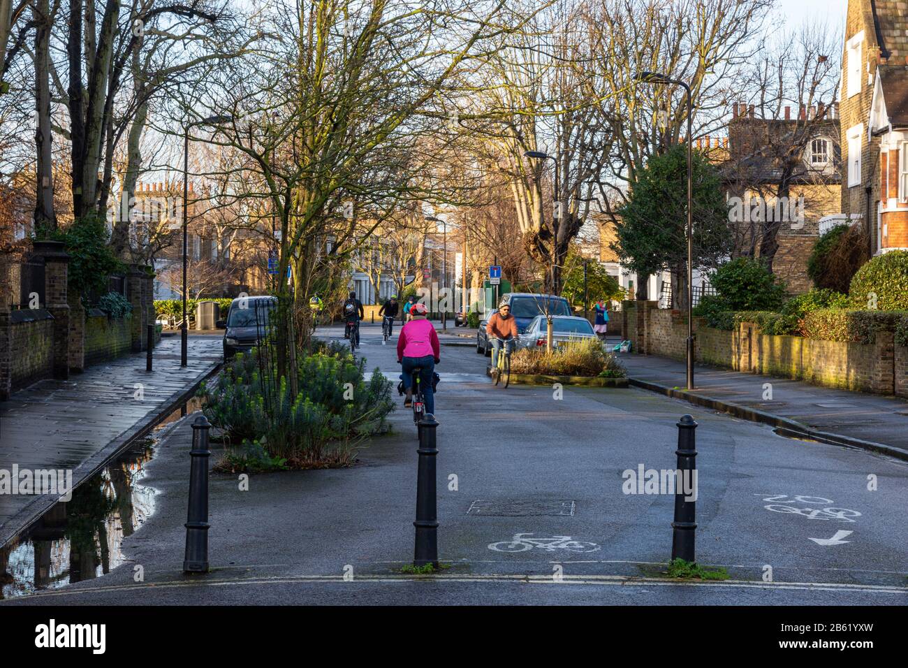 London, England, UK - January 17, 2020: Cyclists ride along residential streets that make up the Quietway 2 cycleway route in Hackney, past bollards t Stock Photo