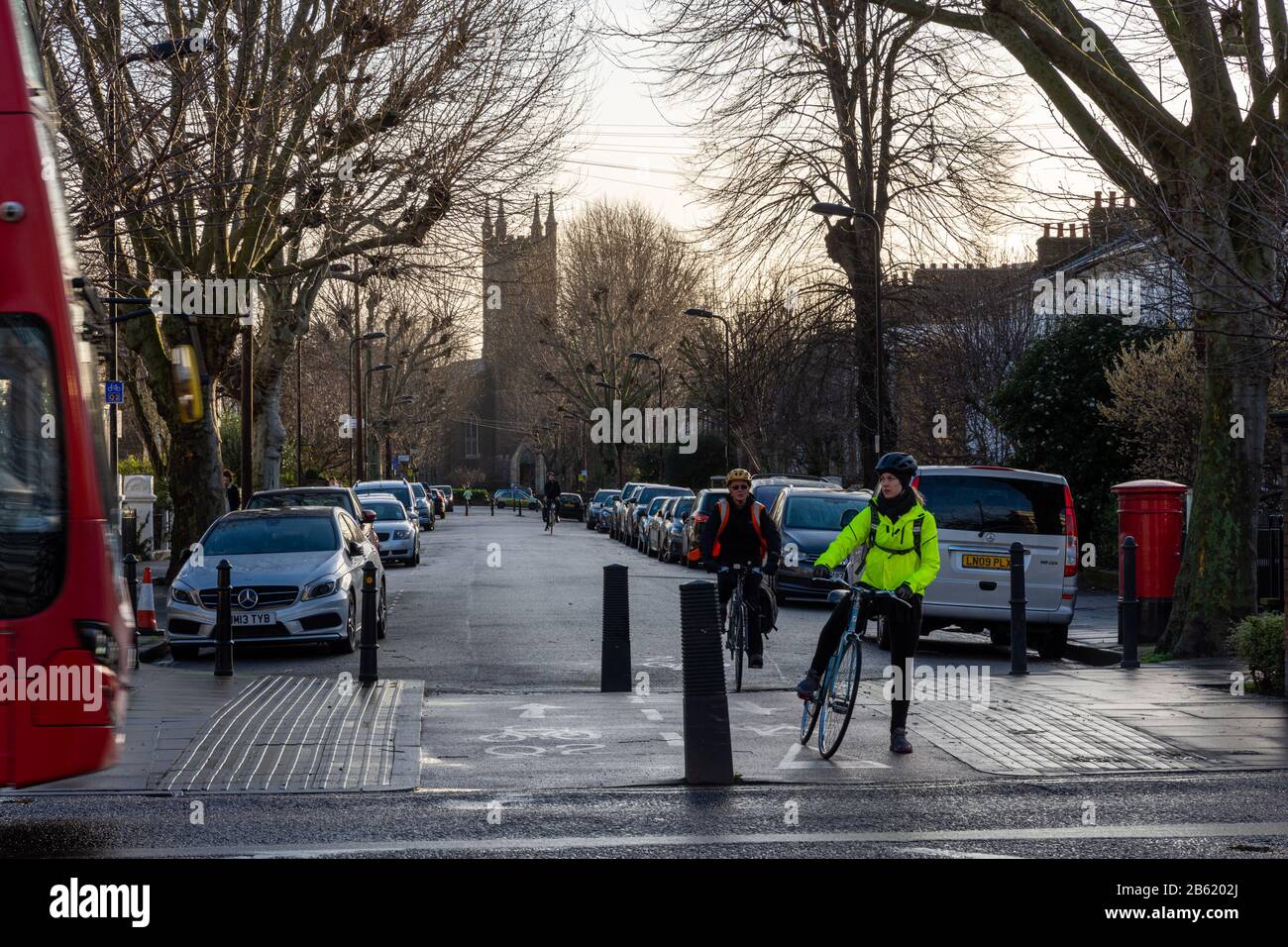 London, England, UK - January 17, 2020: Cyclists ride along residential streets that make up the Quietway 2 cycleway route in Hackney, past bollards t Stock Photo
