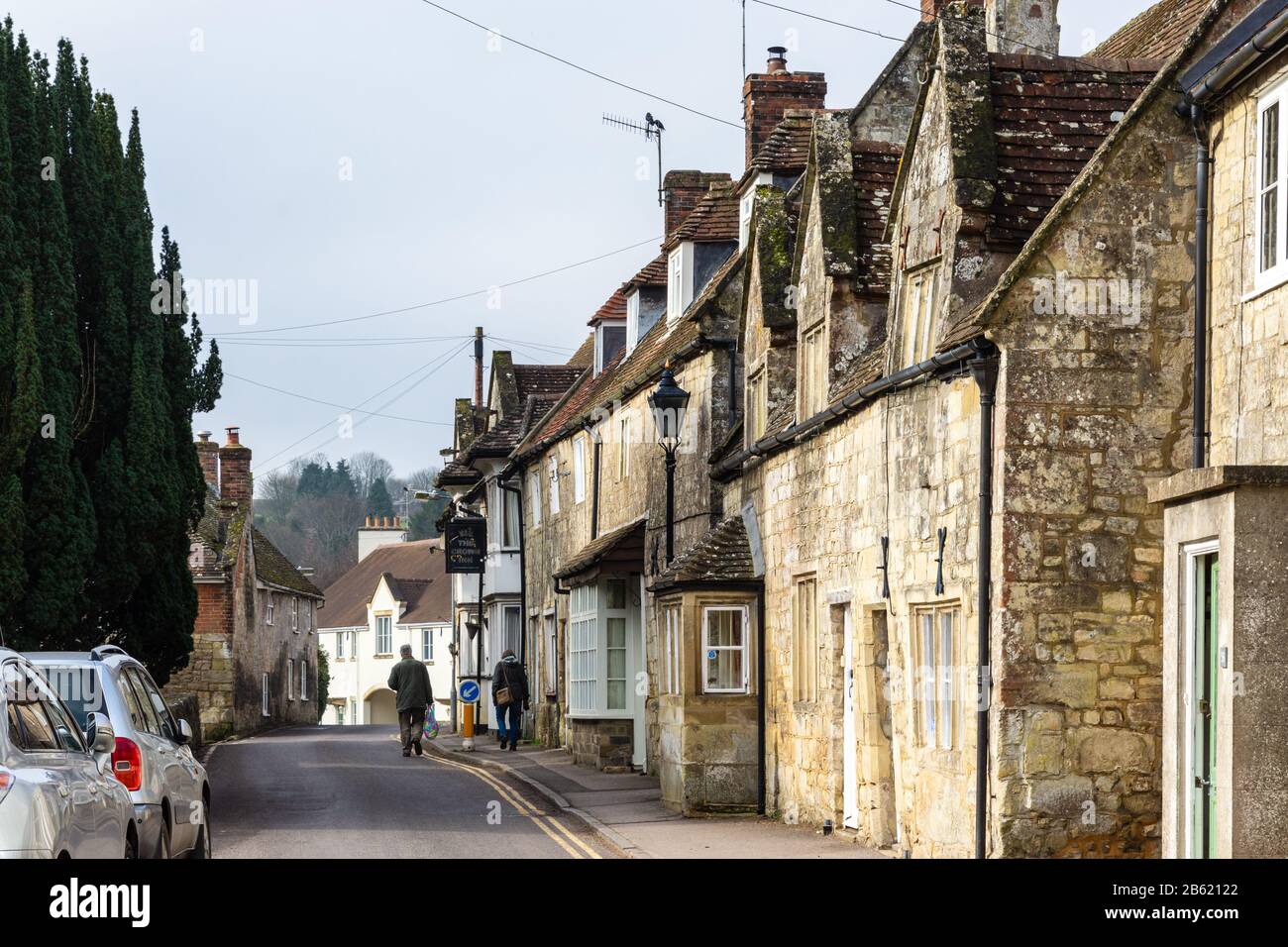 Tisbury, England, UK February 18, 2017 Pedestrians walk past traditional stone cottages in