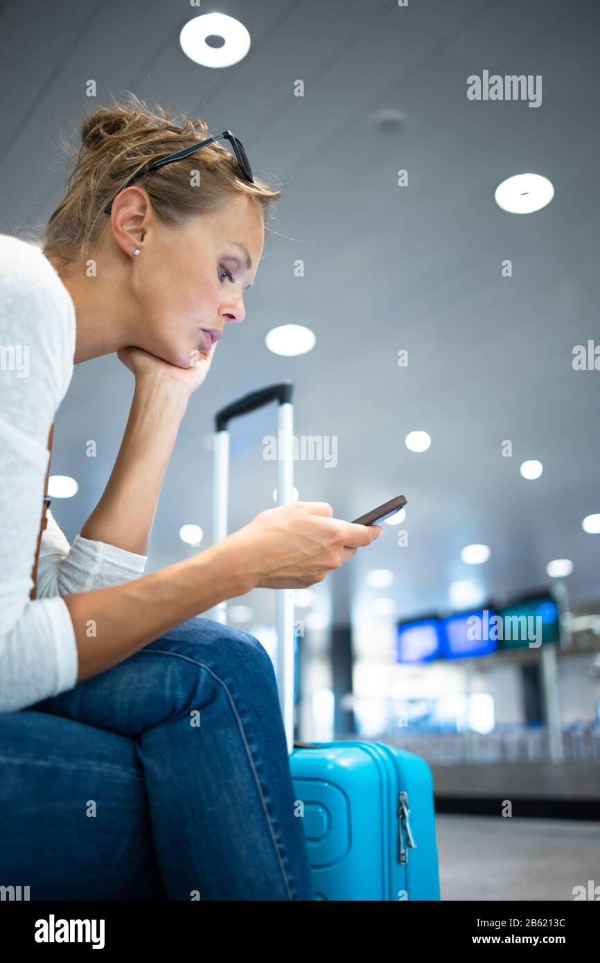 Young woman with her luggage at an international airport, before going through the check-in and the security check before her flight Stock Photo