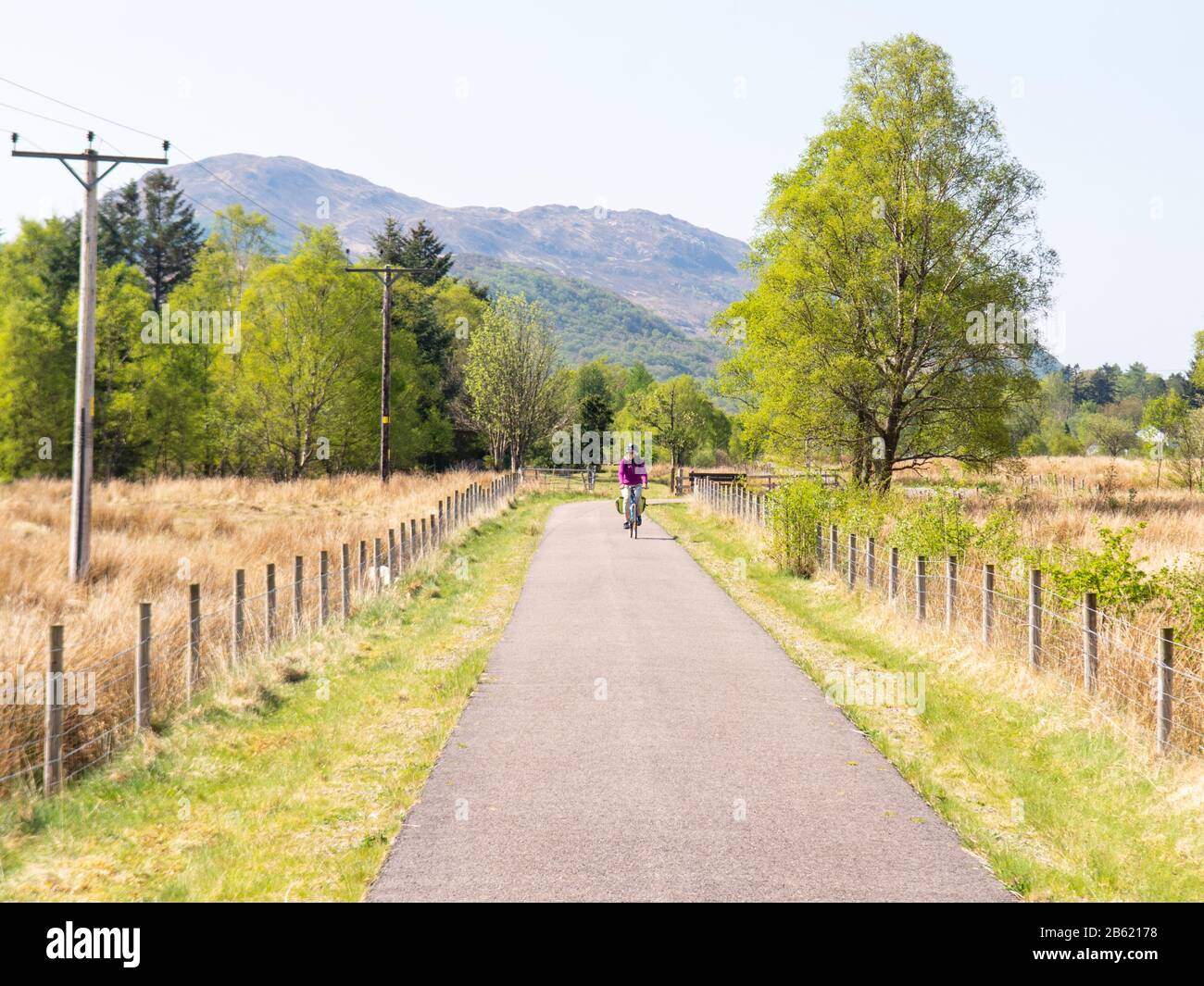 Oban, Scotland, UK - May 12, 2016: A touring cyclist rides through countryside in Appin in the Scottish Highlands on the Caledonia Way, part of the Na Stock Photo