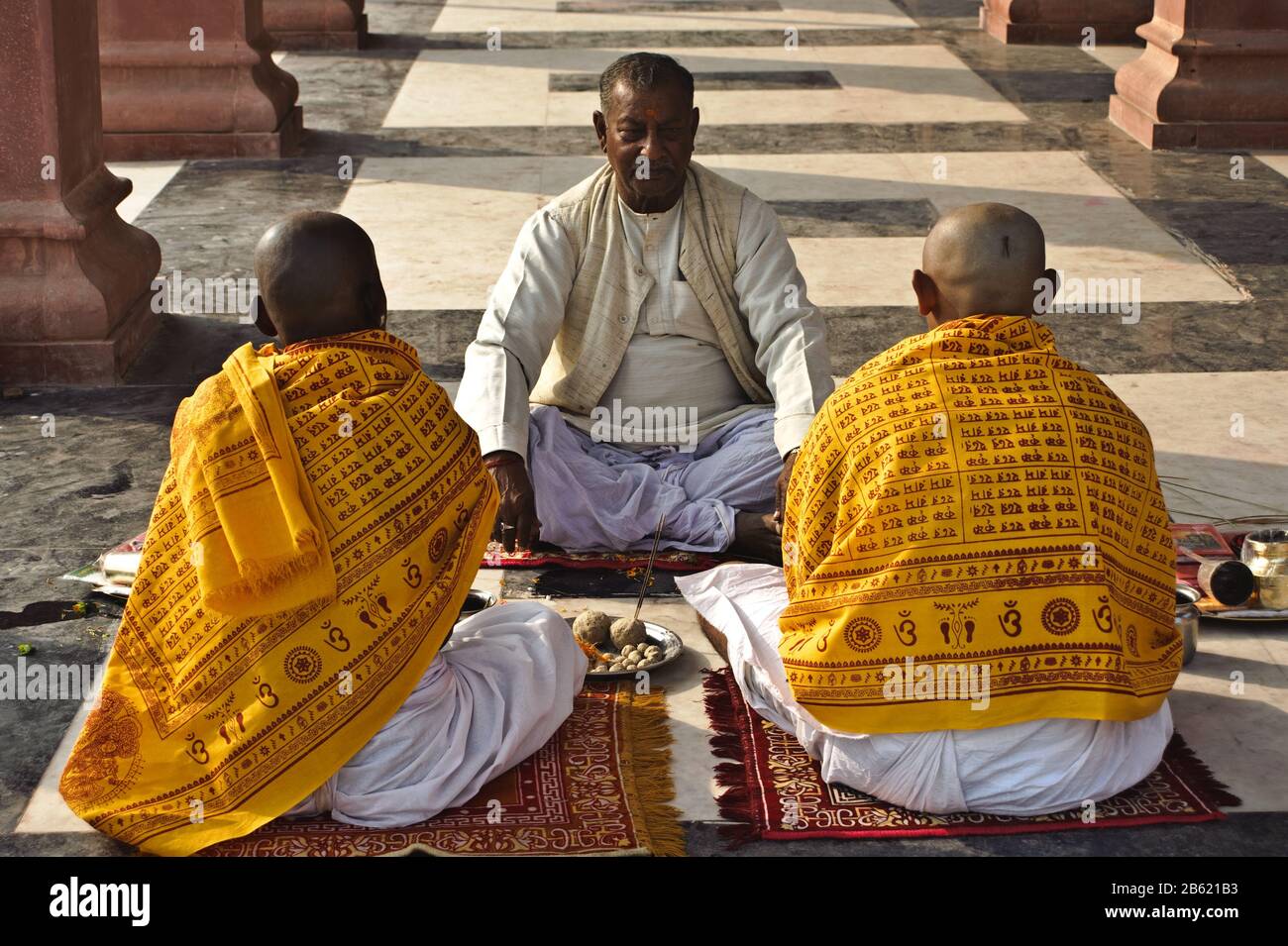 Hindu men ( seen from the rear) are performing a ritual to honour their dead ancestors with the help of a brahman ( india) Stock Photo