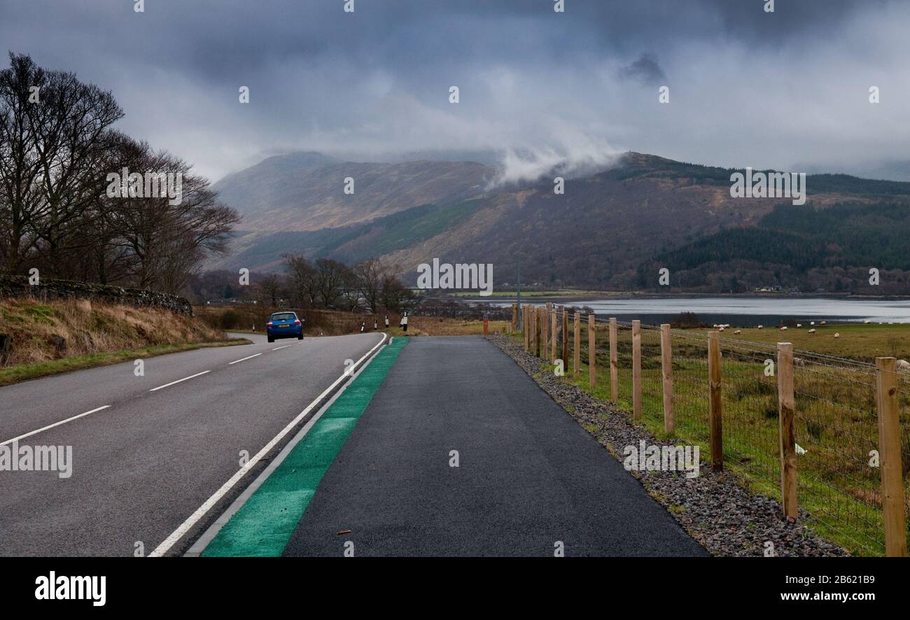 The National Cycle Network 'Caledonia Way' runs alongside the A828 road at Creagan in Appin, with Creach Bheinn mountain rising behind, in the Highlan Stock Photo