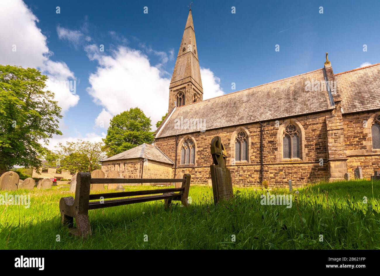 Bamford, England, UK - May 19, 2011: Sun shines on the spire and graveyard of St John's Church in Bamford in the English Peak District. Stock Photo