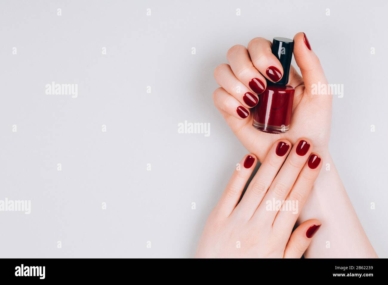 Hands of a young woman with dark red manicure on nails Stock Photo by  Olena_Rudo